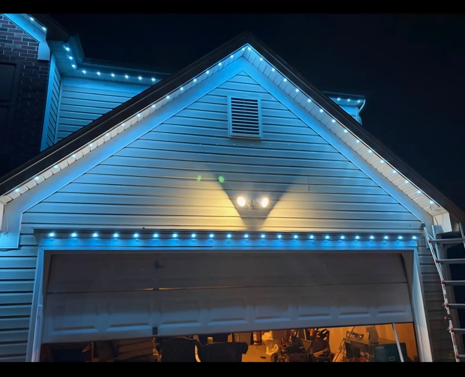 Vinyl-sided gable and garage outlined in cool blue lights