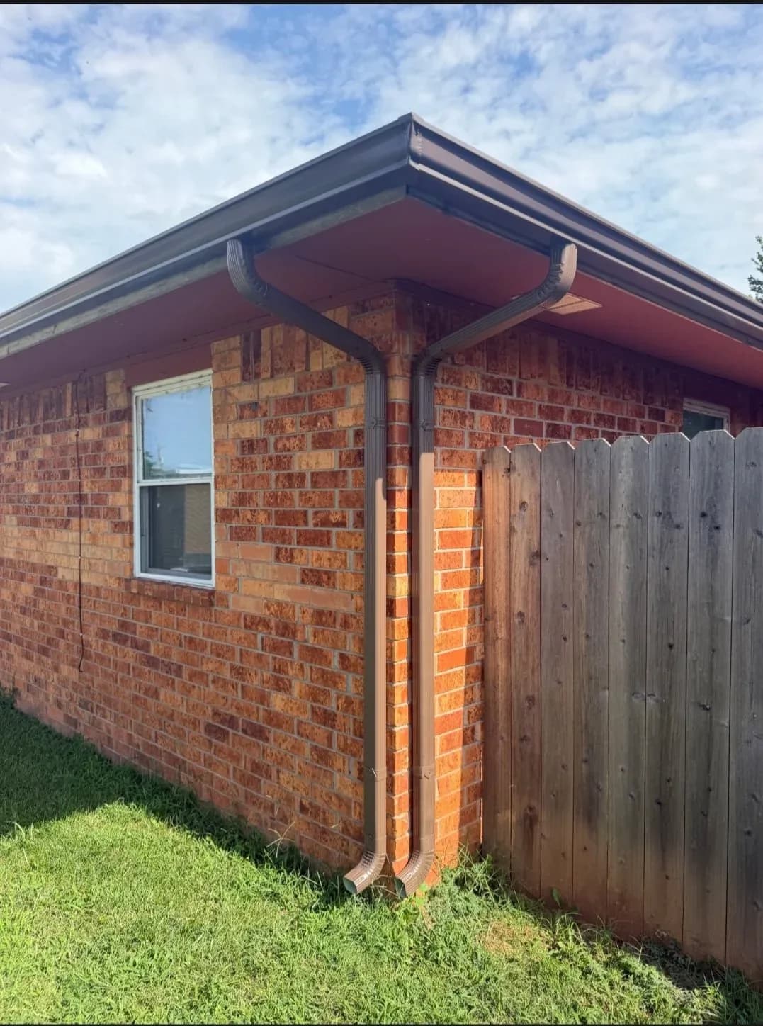 New seamless gutter and downspout on a brick corner