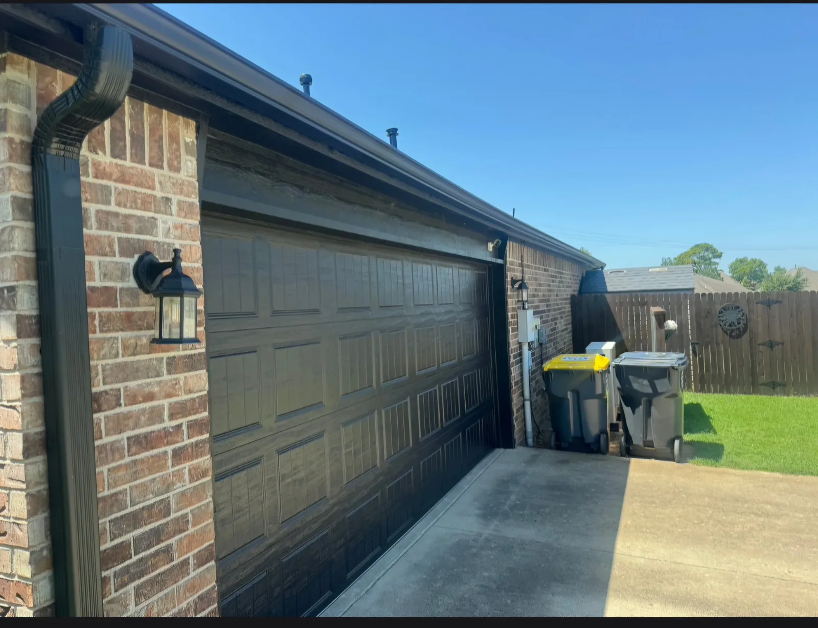 Seamless gutter and downspout beside a garage