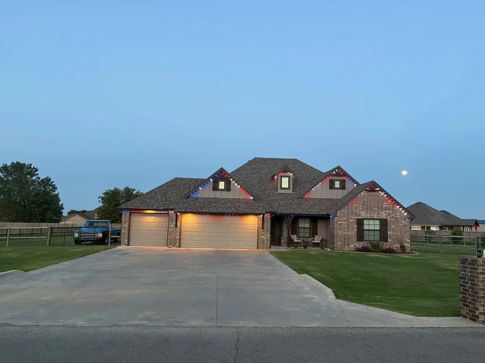 Brick home lit warm at dusk from the driveway